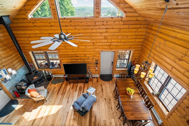8406 S Shire Rd, Vanderbilt, MI 49795 - living area with a wood stove, a towering ceiling, rustic walls, ceiling fan, and hardwood / wood-style floors
