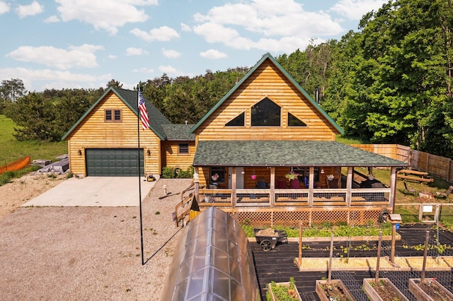 8406 S Shire Rd, Vanderbilt, MI 49795 - view of front of property featuring a vegetable garden, concrete driveway, covered porch, a shingled roof, and a detached garage