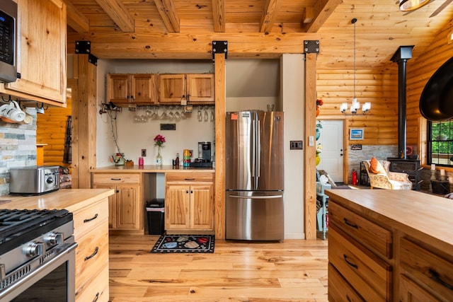 8406 S Shire Rd, Vanderbilt, MI 49795 - kitchen featuring stainless steel appliances, butcher block counters, rustic walls, a wood stove, and light wood-type flooring