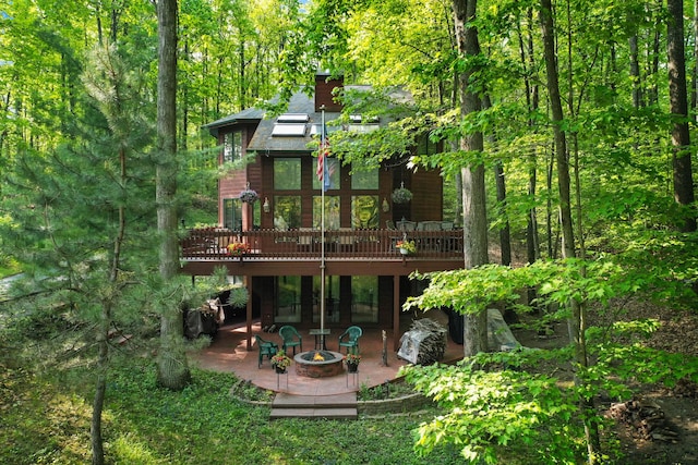 211 Gardners Grv, Roscommon, MI 48653 - back of property featuring a patio, an outdoor fire pit, a deck, and a view of trees