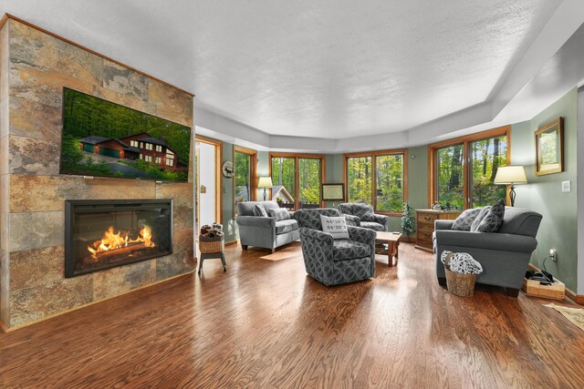 211 Gardners Grv, Roscommon, MI 48653 - living area featuring wood finished floors, a tiled fireplace, baseboards, and a textured ceiling