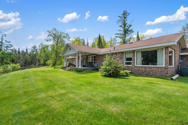 3869 Club Rd, Indian River, MI 49749 - back of property featuring brick siding, a lawn, and cooling unit