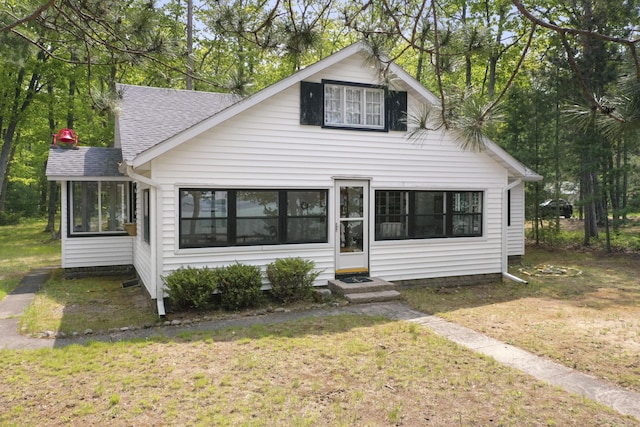 215 Pine Bluffs Rd, Roscommon, MI 48653 - view of front of home featuring a sunroom, entry steps, a shingled roof, and a front lawn