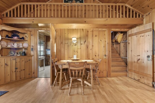 215 Pine Bluffs Rd, Roscommon, MI 48653 - dining room featuring vaulted ceiling, wood walls, wood finished floors, and stairway