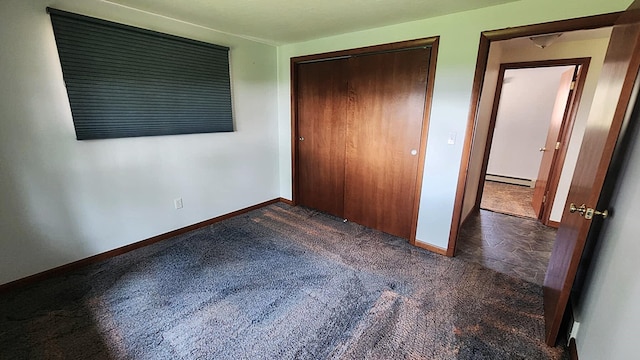 220 Mcdonald Dr, Houghton Lake, MI 48629 - unfurnished bedroom featuring dark colored carpet, a baseboard radiator, and a closet