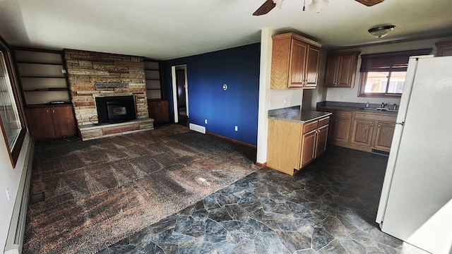 220 Mcdonald Dr, Houghton Lake, MI 48629 - kitchen with freestanding refrigerator, ceiling fan, open floor plan, dark stone finish flooring, and a fireplace