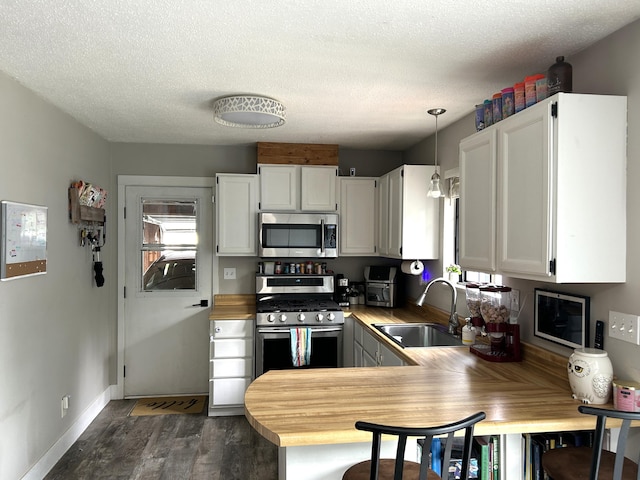 1200 Crestview Dr, Alpena, MI 49707 - kitchen featuring stainless steel appliances, a sink, dark wood-style flooring, white cabinetry, and a textured ceiling