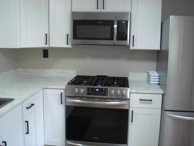 3123 Lovells Rd, Grayling, MI 49738 - kitchen with stainless steel appliances, white cabinetry, and light stone counters