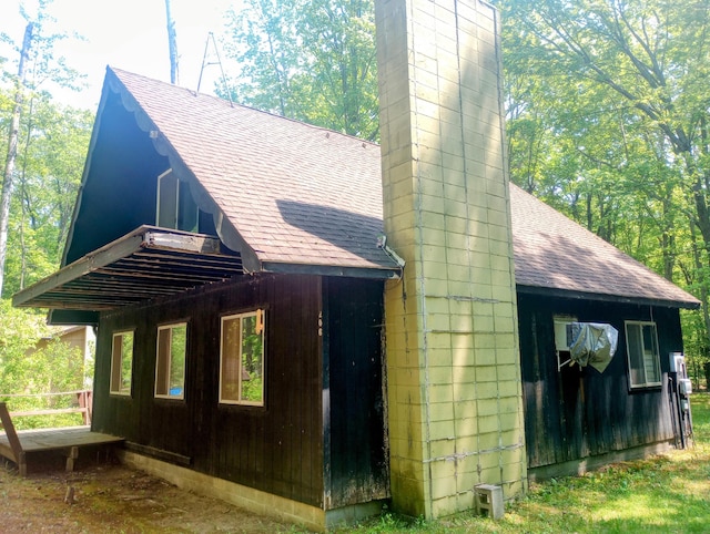 206 Redwine Dr, Houghton Lake, MI 48629 - view of property exterior featuring roof with shingles and a chimney