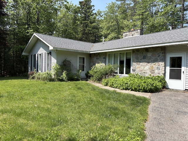 20730 E Riverside Dr, Hillman, MI 49746 - ranch-style house with stone siding, a front yard, a chimney, and roof with shingles
