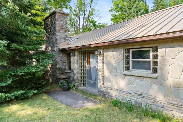 9150 W M-68, Indian River, MI 49749 - entrance to property with a standing seam roof, stone siding, a metal roof, and a chimney