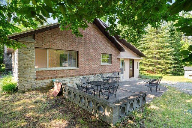 9150 W M-68, Indian River, MI 49749 - back of property featuring brick siding, stone siding, and a patio area