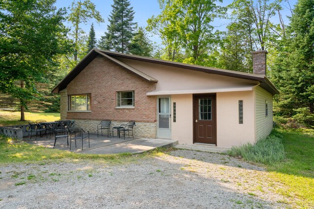 9150 W M-68, Indian River, MI 49749 - rear view of house with a patio area, a chimney, and brick siding