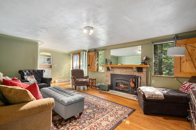 9150 W M-68, Indian River, MI 49749 - living area featuring a baseboard heating unit, wood finished floors, and a brick fireplace