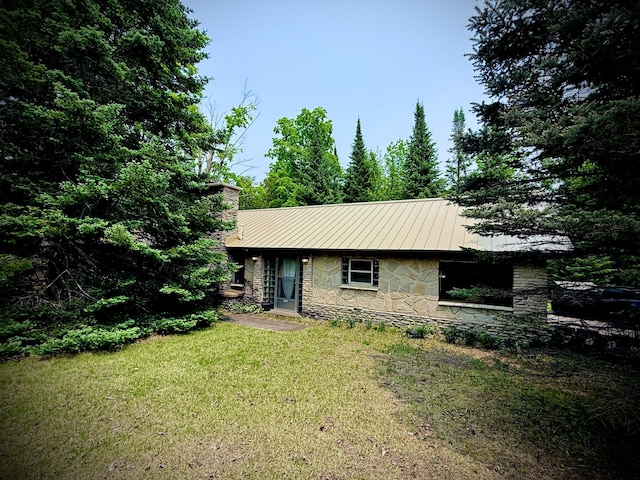 9150 W M-68, Indian River, MI 49749 - view of front facade featuring stone siding, a front yard, a metal roof, and a chimney