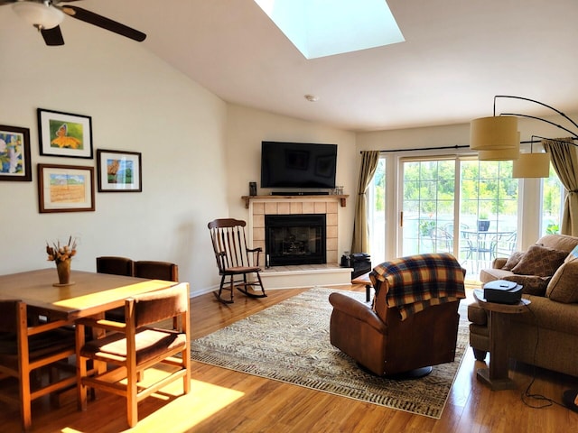 166 Long Rapids Rd, Alpena, MI 49707 - living area with vaulted ceiling, a tile fireplace, wood finished floors, ceiling fan, and a skylight