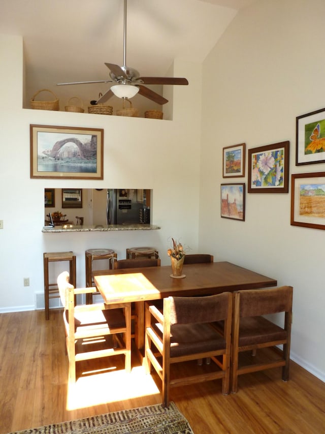 166 Long Rapids Rd, Alpena, MI 49707 - dining room with wood finished floors, ceiling fan, baseboards, and high vaulted ceiling