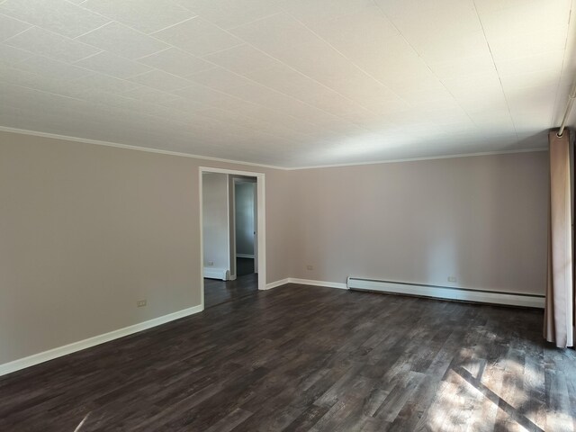 206 N Sixth St, Roscommon, MI 48653 - unfurnished room featuring a baseboard heating unit, dark wood finished floors, crown molding, and baseboards