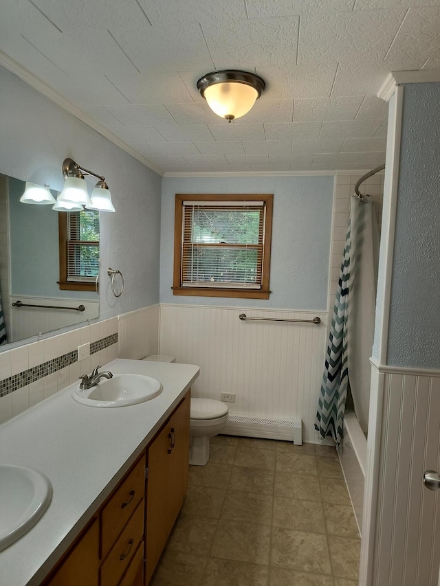 206 N Sixth St, Roscommon, MI 48653 - full bathroom featuring baseboard heating, toilet, double vanity, wainscoting, and ornamental molding