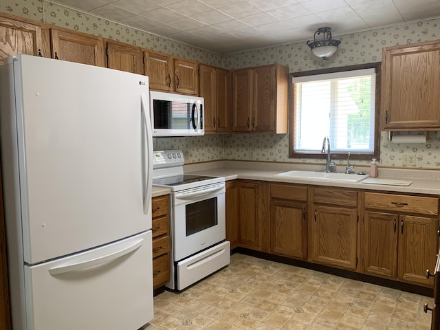 14501 3rd St, Hubbard Lake, MI 49747 - kitchen with white appliances, wallpapered walls, light countertops, and brown cabinetry