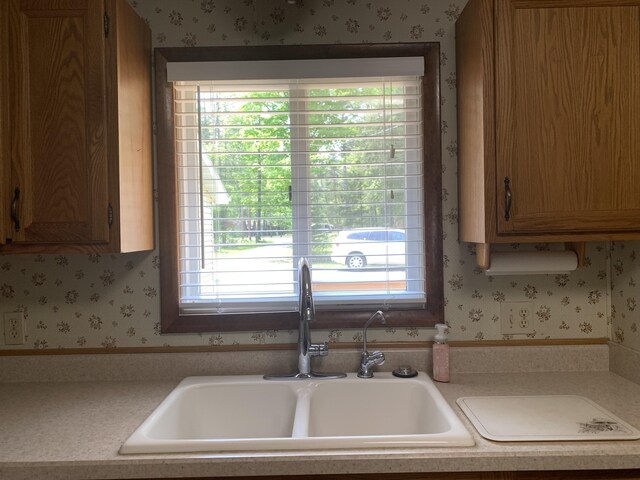 14501 3rd St, Hubbard Lake, MI 49747 - kitchen featuring wallpapered walls, light countertops, and brown cabinetry