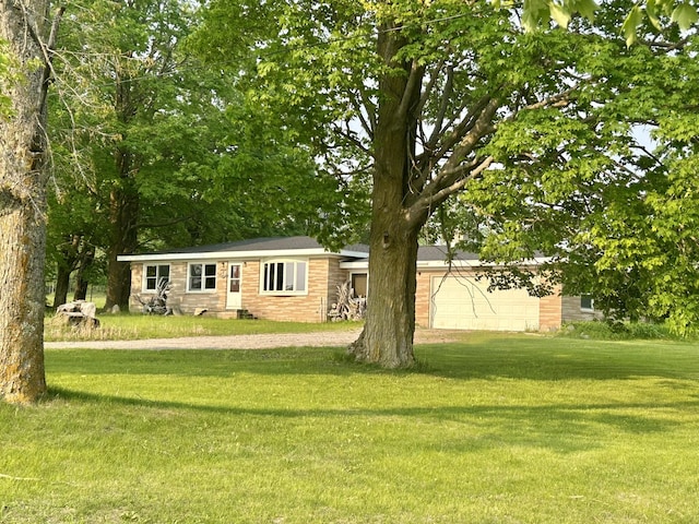 8091 Truax Rd, Hillman, MI 49746 - view of front facade featuring a front lawn, dirt driveway, a garage, and brick siding