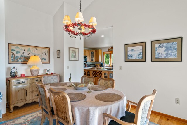 10077 Royal Coachman Trl, Gaylord, MI 49735 - dining area featuring light wood-style flooring, a chandelier, high vaulted ceiling, and baseboards
