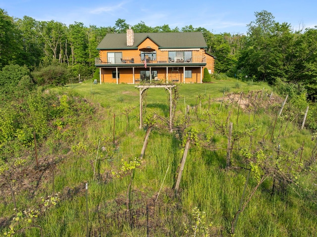 10077 Royal Coachman Trl, Gaylord, MI 49735 - back of property with a deck, a chimney, a wooded view, and a lawn