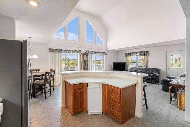 10480 N Straits Hwy, Cheboygan, MI 49721 - kitchen featuring stainless steel fridge with ice dispenser, open floor plan, brown cabinets, plenty of natural light, and high vaulted ceiling