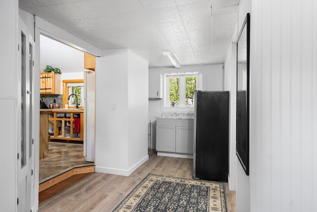 5466 Big Wolf Ln, Lewiston, MI 49756 - kitchen featuring light wood finished floors, freestanding refrigerator, and decorative backsplash