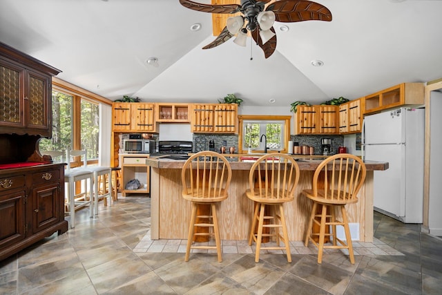 5466 Big Wolf Ln, Lewiston, MI 49756 - kitchen with freestanding refrigerator, vaulted ceiling, stainless steel microwave, open shelves, and a ceiling fan
