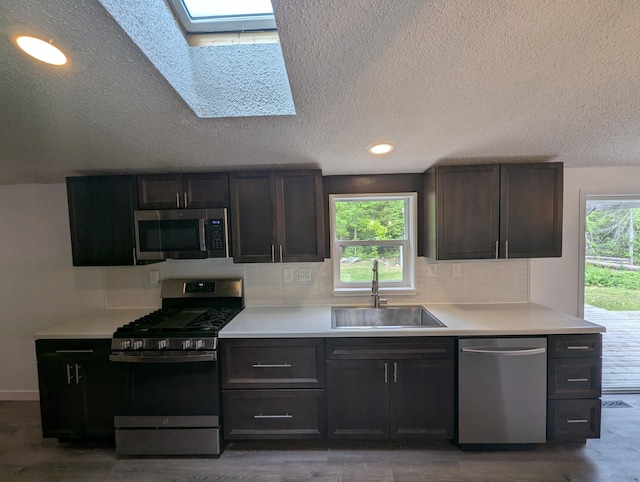 7322 E Grand Lake Rd, Presque Isle, MI 49777 - kitchen with stainless steel appliances, a skylight, decorative backsplash, a textured ceiling, and wood finished floors