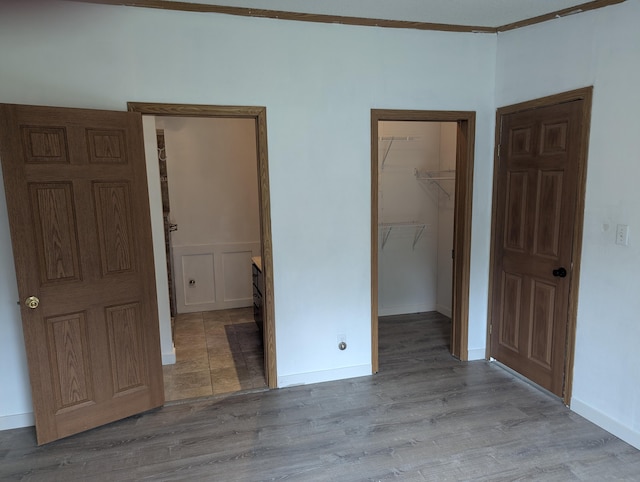 7322 E Grand Lake Rd, Presque Isle, MI 49777 - unfurnished bedroom with wood finished floors, a walk in closet, a closet, and wainscoting