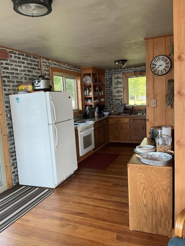3606 S St, Lupton, MI 48635 - kitchen with white appliances, dark wood-style flooring, healthy amount of natural light, and brick wall