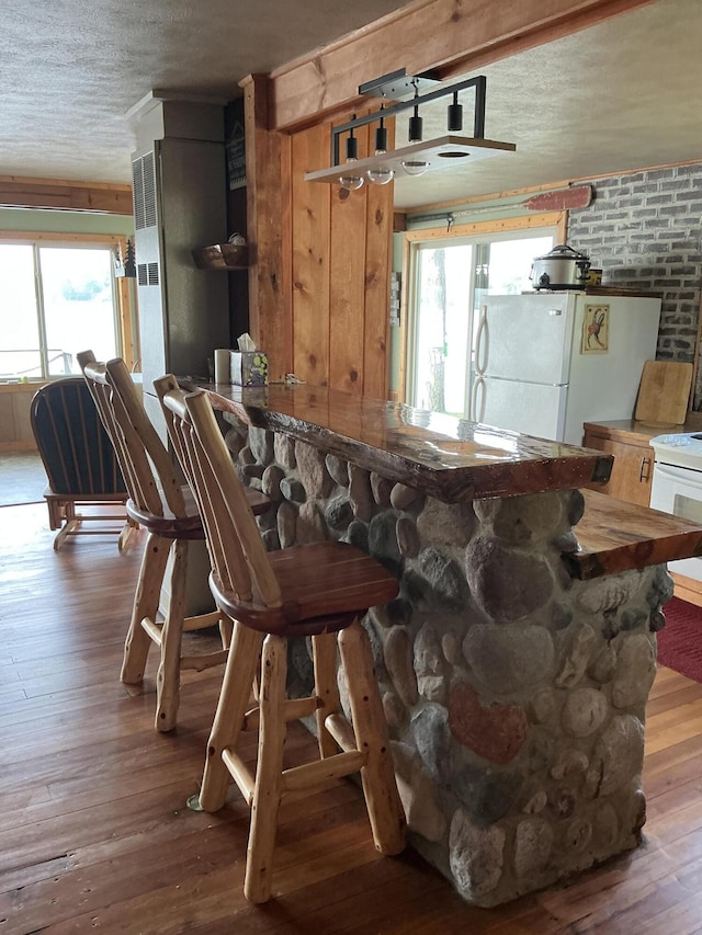 3606 S St, Lupton, MI 48635 - kitchen with white appliances, healthy amount of natural light, a textured ceiling, hardwood / wood-style floors, and wooden walls