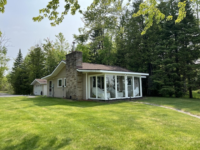 7811 Mcdonald Rd, Cheboygan, MI 49721 - back of property featuring a sunroom, a lawn, a chimney, and an attached garage
