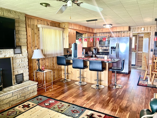 7811 Mcdonald Rd, Cheboygan, MI 49721 - kitchen with appliances with stainless steel finishes, wooden walls, ceiling fan, dark wood-type flooring, and a peninsula