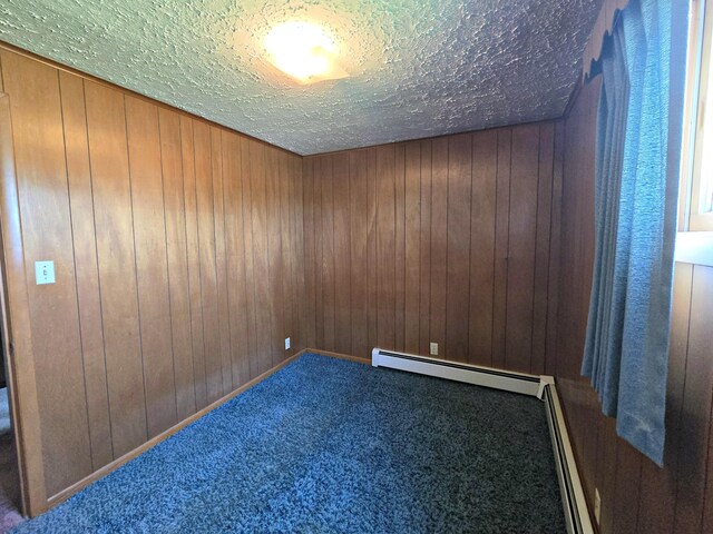 200 S 1st St, Saint Ignace, MI 49781 - carpeted empty room with wooden walls, a textured ceiling, baseboard heating, and a baseboard radiator