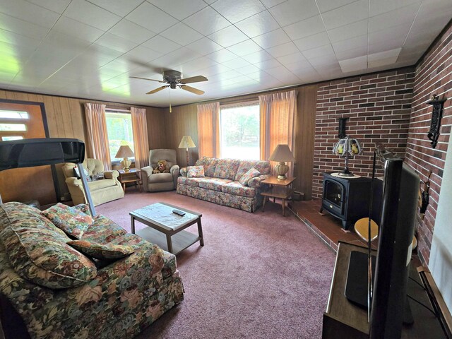 200 S 1st St, Saint Ignace, MI 49781 - carpeted living area with a wood stove, ceiling fan, and wooden walls