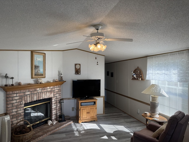 3981 Pointe Dr, Carp Lake, MI 49718 - living area featuring wood finished floors, lofted ceiling, ceiling fan, a decorative wall, and a fireplace