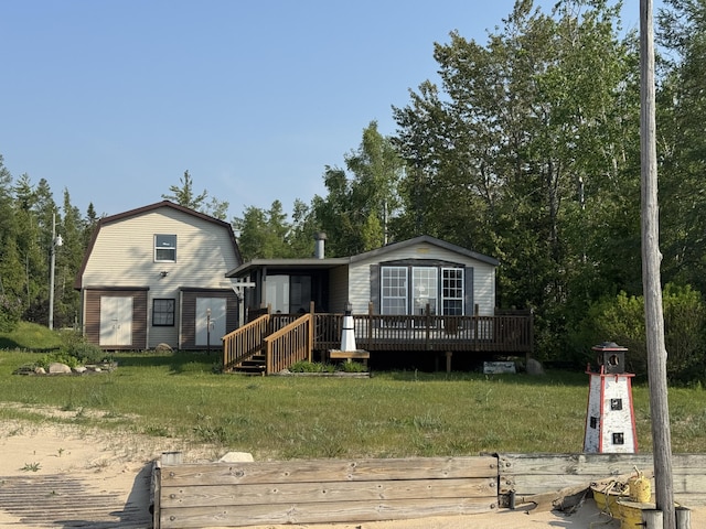 3981 Pointe Dr, Carp Lake, MI 49718 - view of front facade with a wooden deck, a front lawn, and a gambrel roof