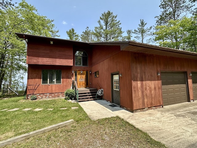 9561 Highbanks Dr, Cheboygan, MI 49721 - view of front of home featuring a front lawn, a garage, and concrete driveway