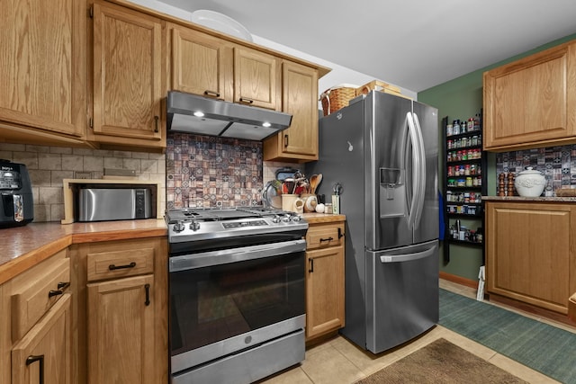 104 Alpena Trl, Houghton Lake, MI 48629 - kitchen with appliances with stainless steel finishes, under cabinet range hood, light tile patterned flooring, backsplash, and light countertops