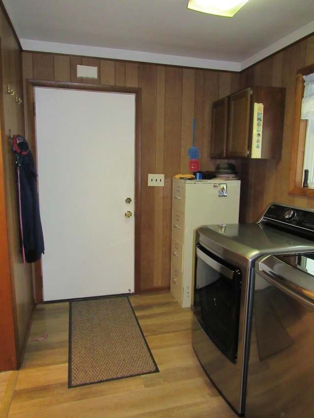 110 Chippewa Trl, Prudenville, MI 48651 - laundry room featuring wooden walls, independent washer and dryer, light wood-style floors, and cabinet space