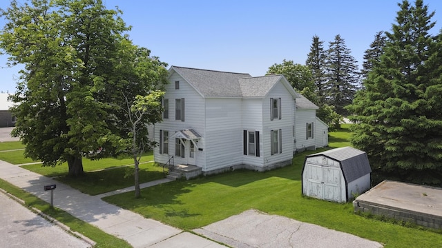 757 N Main St, Cheboygan, MI 49721 - view of home's exterior with a storage unit, a shingled roof, and a lawn