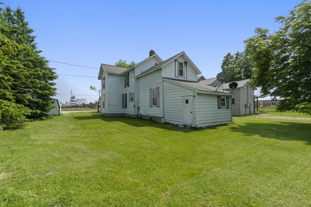757 N Main St, Cheboygan, MI 49721 - view of side of property featuring a yard, roof with shingles, and a chimney