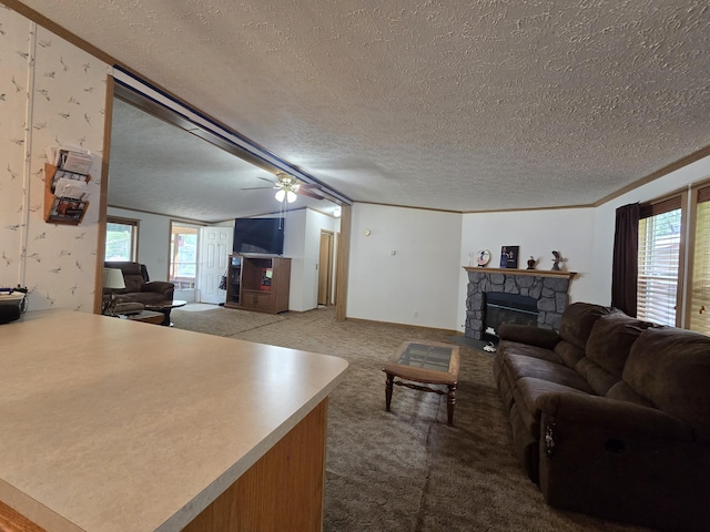 6709C E Houghton Lake Dr, Houghton Lake, MI 48629 - living room featuring a textured ceiling, carpet, a stone fireplace, ceiling fan, and crown molding