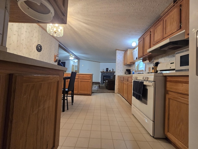6709C E Houghton Lake Dr, Houghton Lake, MI 48629 - kitchen with white stove, wallpapered walls, under cabinet range hood, brown cabinetry, and light countertops