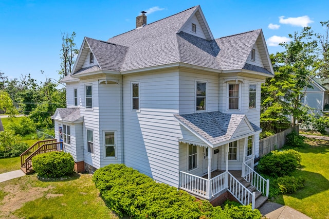 220 E Main St, Gaylord, MI 49735 - view of home's exterior with a shingled roof, a yard, a chimney, and stairway