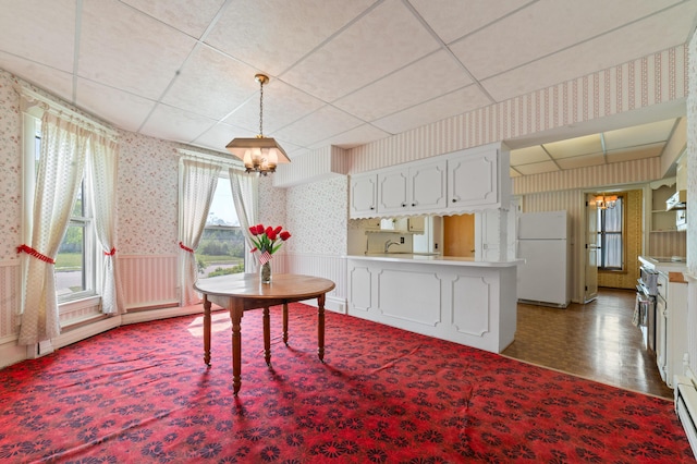 220 E Main St, Gaylord, MI 49735 - dining room featuring wallpapered walls, a chandelier, wainscoting, and a baseboard heating unit